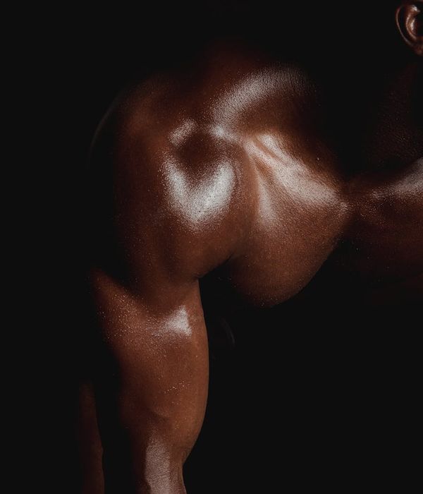 Man performing a strength exercise in a modern, dark gym.